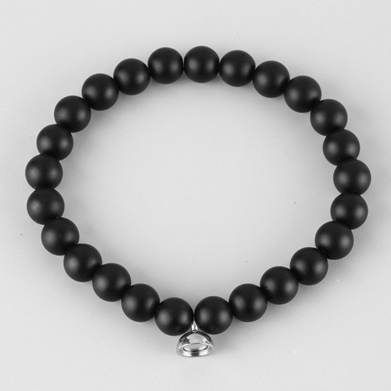 Flat lay of a bracelet made of matte black round beads with a small silver clasp charm 2