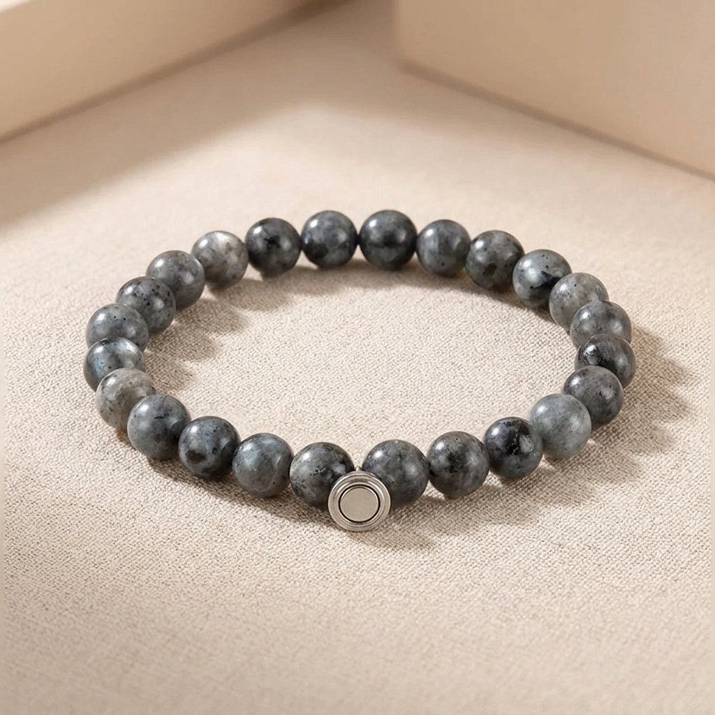 Bracelet of gray speckled stone beads with a round silver magnetic clasp, resting on a textured beige surface 3