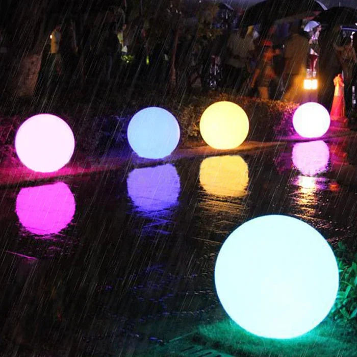 Spheres glowing pink, blue, yellow, purple and white by a wet pavement in the rain 16