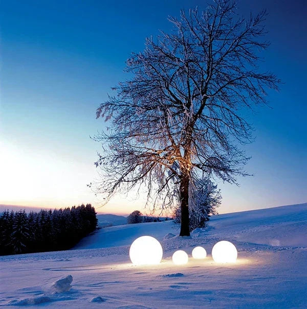 Four glowing spheres on snow beneath a bare frosted tree at twilight 19