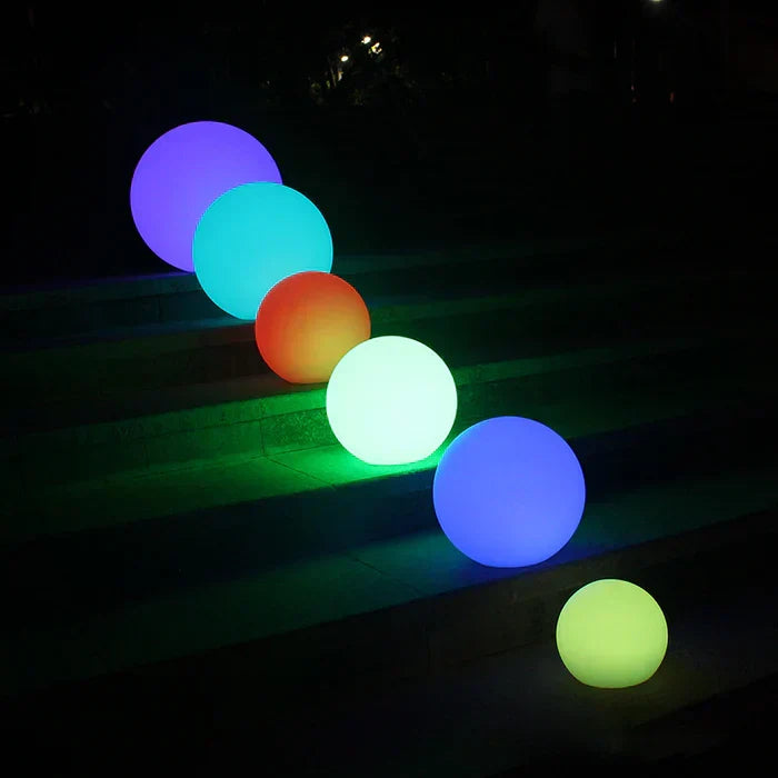 Six glowing spheres of different sizes in purple, teal, orange, white, blue and yellow-green on dark outdoor steps at night 21