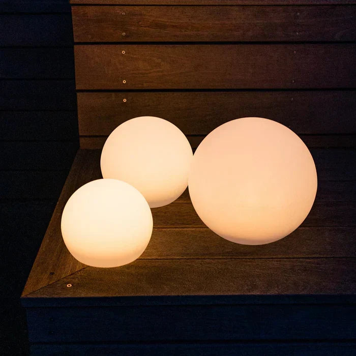 Three warm-glowing spheres of different sizes resting on a dark wooden bench 3