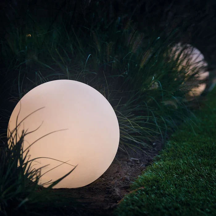 Single large sphere with a soft warm glow sitting among tall grasses beside a lawn 4