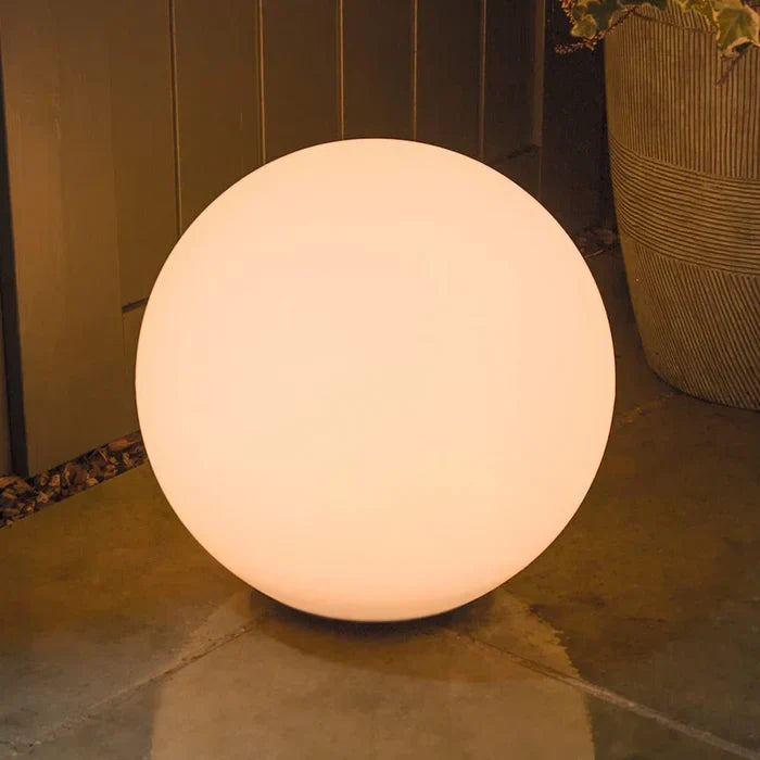 Large warm-glowing sphere on a stone patio beside a wooden fence and planter 6