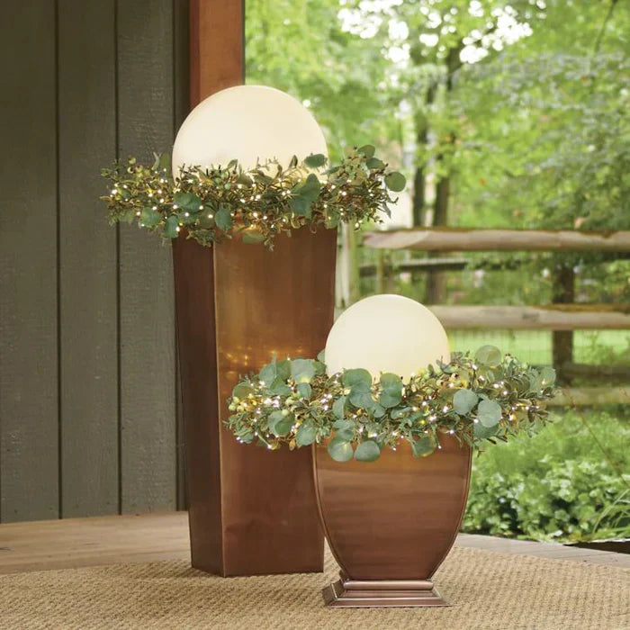 Two spheres set on copper planters, surrounded by eucalyptus garlands with tiny string lights 8