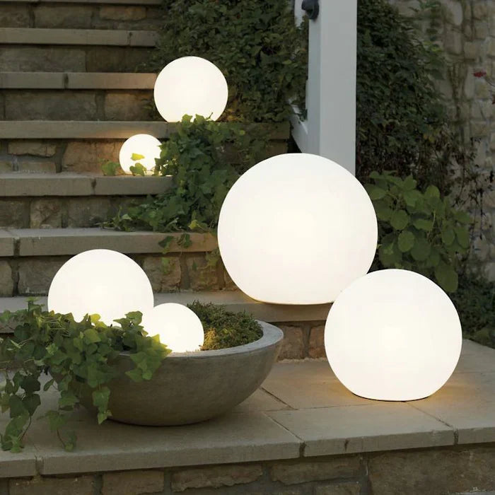 Glowing white spheres of several sizes lit on stone garden steps and in a planter 1