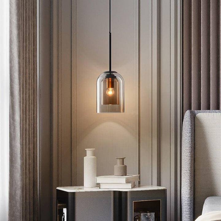 Single amber pendant glowing beside a bed, above a marble-topped nightstand with vases and books 3