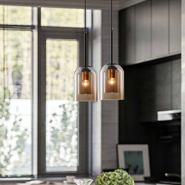 Two amber double-glass pendants hang in a kitchen with a large window and dark cabinets 4