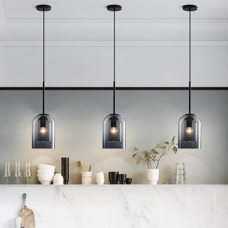 Three smoke gray pendants hang in a row above a white marble counter with dishes 5