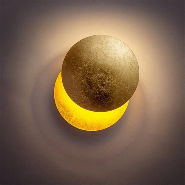 Close front view of a gold disc overlapping a glowing yellow crescent, casting a soft halo on the wall 5