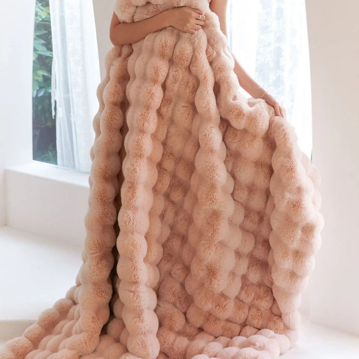 Model holds a peach-pink textured blanket against her body, its bubble-like fluffy pile hanging to the floor 4