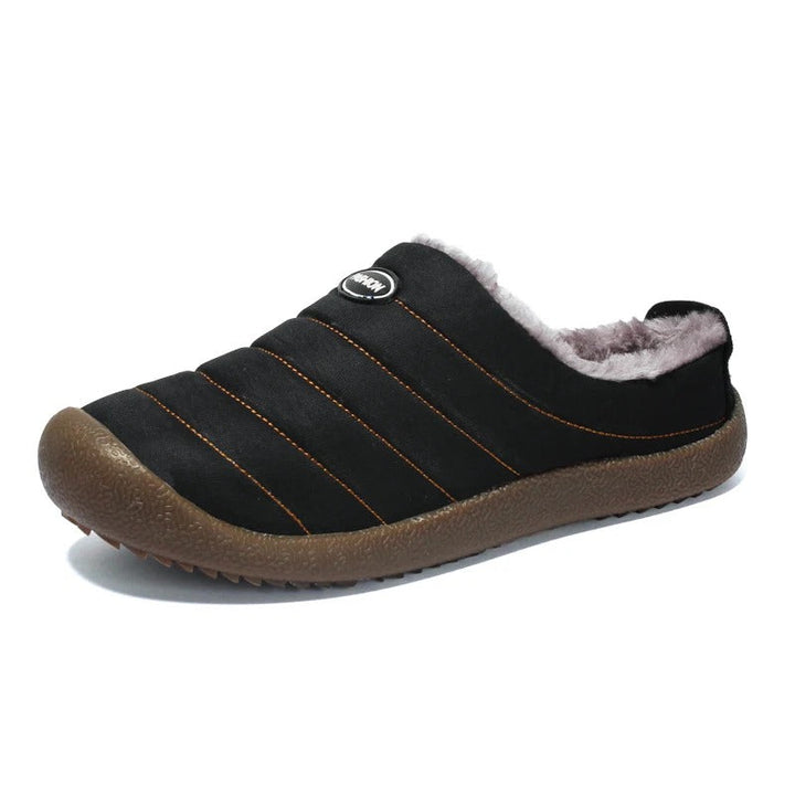 Single black quilted slipper on white background with orange stitching and gray fleece lining 16