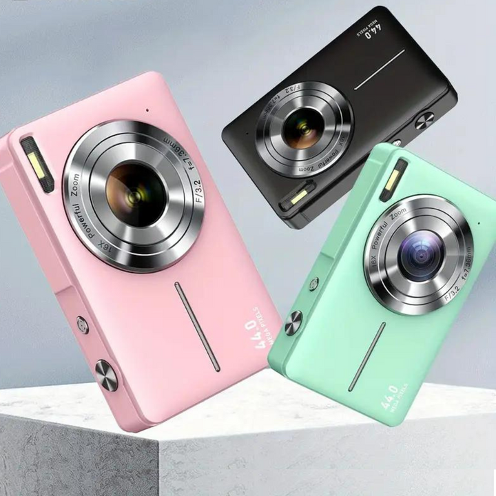 Pink, black and mint green compact cameras tilted in the air above a white stone block 1