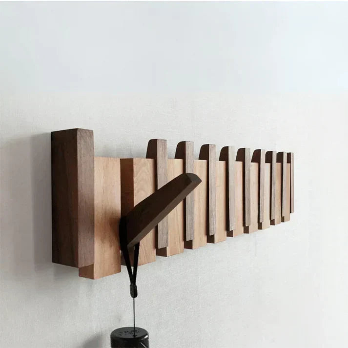 Angled view of the wooden rack on a white wall with one hook folded out 2