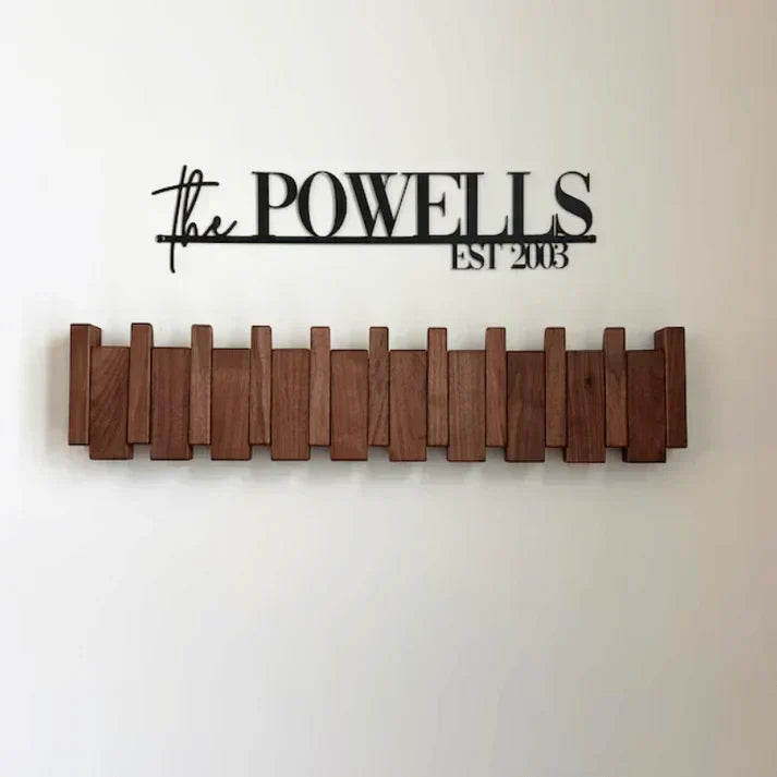 Dark wooden rack mounted below a black metal family name sign on a white wall 6